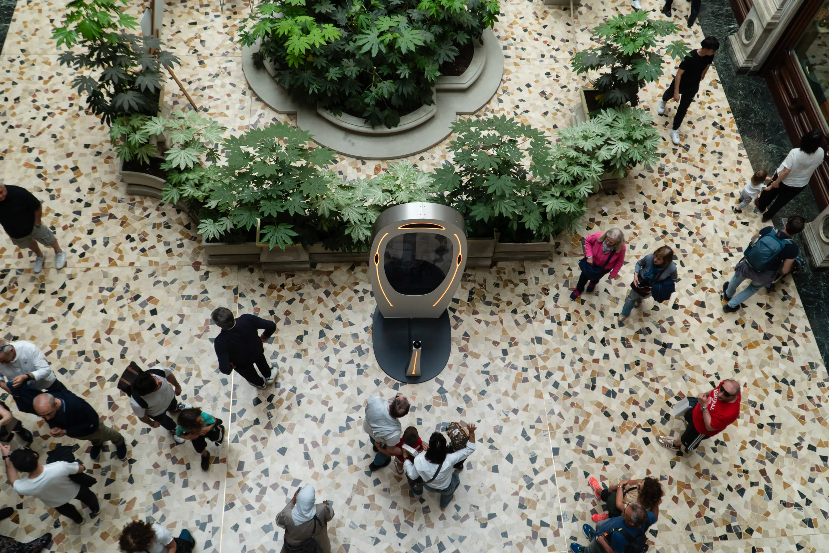 Seen from above: visitors walking around a Poem Booth on a terrazzo floor in Turin.